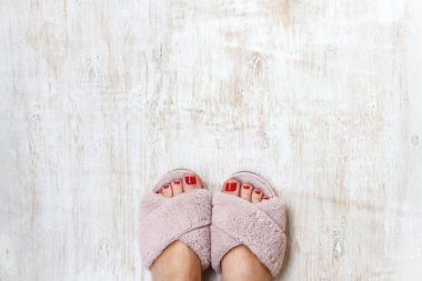 bir evde kırmızı tırnaklı kadın bacakları kürk kabarık pembe terlik