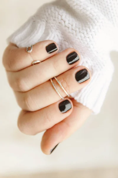 hand with black manicure and rings on the phalanges on short nai
