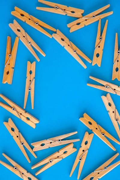 Pinzas de tela amarillas de madera están dispersas en un fondo azul-cian — Foto de Stock
