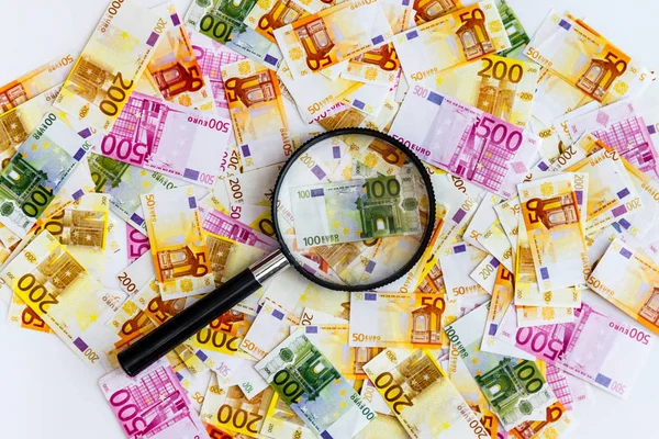 A lot of euro banknotes on a white background and a magnifying g — Stock Photo, Image