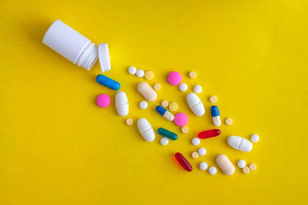 Разнообразие лекарственных таблеток и таблеток, выливающихся из флакона на — стоковое фото