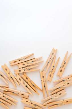 Beyaz arka plana saçılmış ahşap mandallar. Yukarıdan bak. Boşluğu kopyala