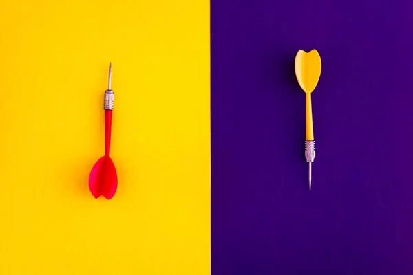 Veelkleurige rood geel groene Darts pijlen op geel Violet blauwe achtergrond. Platte lag. Uitzicht van bovenaf. Kopieer ruimte. Het concept van het raken van het doelwit, toewijding — Stockfoto