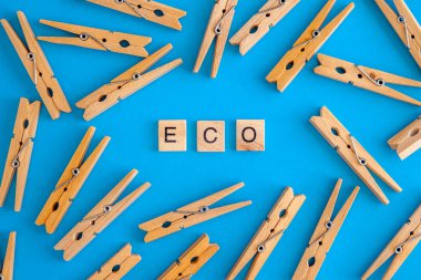Ahşap clothespins kelime Eko ve doğal ile beyaz ve mavi arka planda dağılmış. Yukarıdan görüntüle. Boşluk Kopyala. Düz yatıyordu. Konsept doğal, çevre dostu