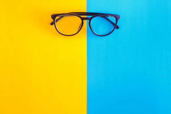 Gafas con estilo sobre un fondo azul-cian y amarillo-naranja brillante, vista superior, aislado. Copiar espacio. Puesta plana — Foto de Stock