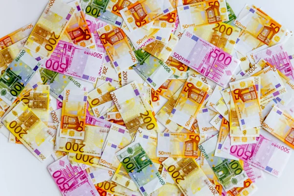 A lot of euro banknotes on a white background and a magnifying glass on top, top view — Stock Photo, Image