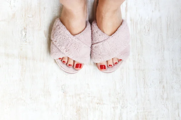 Женские ноги с красными ногтями в домашнем мехе пушистые розовые тапочки на светлом деревянном фоне. Плоский лежал. Вид сверху. Концепция уютного светлого девичьего дома — стоковое фото