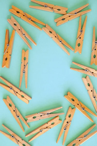 Houten gele wasknijpers zijn verspreid over een cyaan-blauwe achtergrond. Frame van wasknijpers. Uitzicht van bovenaf. Kopieer ruimte. Platte lag. Het concept is natuurlijk, milieuvriendelijk — Stockfoto