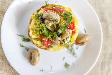 Mantar, domates ve sebze ile pişmiş patates. Açık bir rustik kumaş arka planda beyaz bir plaka üzerinde hizmet vermektedir. Close. Üst görünüm. Boşluk Kopyala.