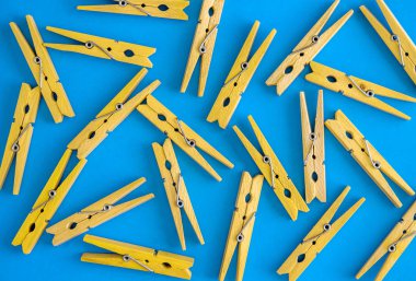 Ahşap sarı clothespins bir mavi-mavi arka planda dağılmış. Clothespins çerçevesi. Yukarıdan görüntüle. Boşluk Kopyala. Düz yatıyordu. Konsept doğal, çevre dostu