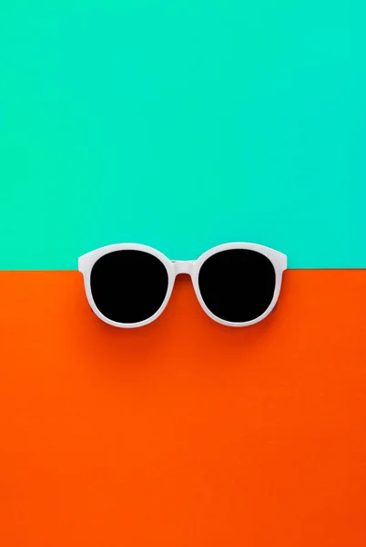 Ηλιόλουστα κομψά λευκά γυαλιά ηλίου σε φωτεινό μπλε-κυανό και κόκκινο-πορτοκαλί φόντο, επάνω θέα, απομονωμένο. Αντιγραφή χώρου. Επίπεδη ωοτοκίδα — Φωτογραφία Αρχείου