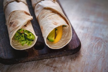 Et, sebze ve peynir ile Lavash rulo yeşil ile servis edilir. Rustik ahşap masada marul salata. Sağlıklı kahvaltı konsepti. Geleneksel Yunan yemekleri-Gyro