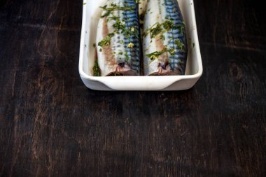 Yeşiller ve otlar iki çiğ balık uskumru karanlık bir arka planda pişmiş olacak. Yukarıdan görüntüle. Retro etkisi