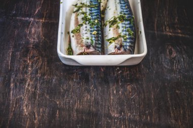 Yeşiller ve otlar iki çiğ balık uskumru karanlık bir arka planda pişmiş olacak. Yukarıdan görüntüle. Retro etkisi