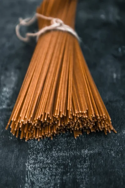 Syrové celozrnné špagety v housku na tmavém pozadí. Pohled shora — Stock fotografie