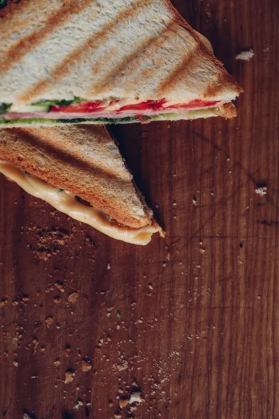나무 배경에 두 개의 샌드위치, 상단 보기. 도마에 햄, 치즈, 양상추 샌드위치를 곁들인 파니니 스택 — 스톡 사진