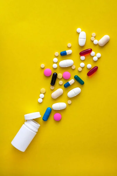 En mängd olika läkemedel piller och piller hälls ut ur flaskan på en gul bakgrund. Flat Lay. Kopiera utrymme. Trend. Konceptet med en hälsosam, ljus, modern medicin och farmakologi — Stockfoto