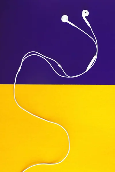 White headphones on a yellow-violet background. View from above. — Stock Photo, Image