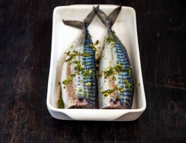 Yeşiller ve otlar iki çiğ balık uskumru karanlık bir arka planda pişmiş olacak. Yukarıdan görüntüle. Retro etkisi