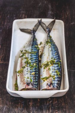 Yeşiller ve otlar iki çiğ balık uskumru karanlık bir arka planda pişmiş olacak. Yukarıdan görüntüle. Retro etkisi