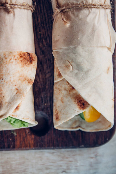 Lavash rolls with meat, vegetables and cheese served with green. Lettuce salad on rustic wooden table. Healthy breakfast concept. Greek traditional food - Gyro