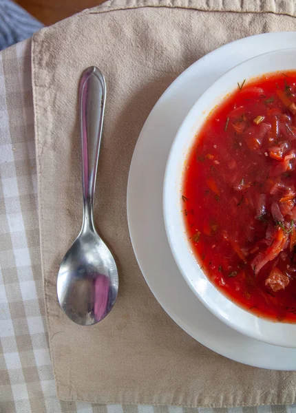 Perinteinen ukrainalais-venäläinen tomaatti borssikeitto smetanalla valkoisella lautasella pöydällä. Näkymä ylhäältä . — kuvapankkivalokuva