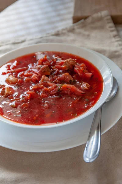 Traditional Ukrainian-Russian tomato borscht soup with sour cream in a white plate on the table. View from above. — Stock Photo, Image