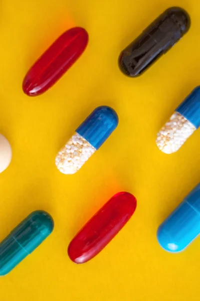 Szétszórt a különböző sokszínű tabletták egy sárga-narancssárga háttér. Kilátás fentről. Közeli — Stock Fotó