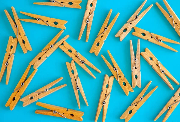 Las pinzas de tela amarillas de madera están dispersas sobre un fondo azul-cian. Marco de pinzas de ropa. Vista desde arriba. Copiar espacio. Acostado. El concepto es natural, ecológico —  Fotos de Stock