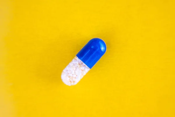 One blue pill capsule isolated on yellow background, close-up, top view, copy space — Stock Photo, Image