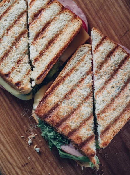 Twee broodjes op een houten achtergrond, Top uitzicht. Een stapel Panini met ham, kaas en sla sandwich op een snijplank — Stockfoto