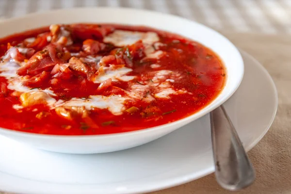 Sopa tradicional de borscht de tomate ucraniano-russo com creme azedo em uma placa branca na mesa. Vista de cima . — Fotografia de Stock