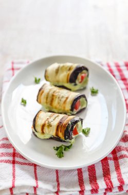 hafif bir arka plan üzerinde beyaz bir tabak üzerinde kızarmış patlıcan, süzme peynir ve domates geleneksel çanak üç rulo. Minimalizm. Yukarıdan görüntüle