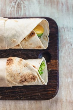 Et, sebze ve peynir ile Lavash rulo yeşil ile servis edilir. Rustik ahşap masada marul salata. Sağlıklı kahvaltı konsepti. Geleneksel Yunan yemekleri-Gyro