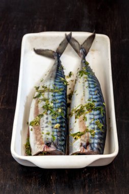 Yeşiller ve otlar iki çiğ balık uskumru karanlık bir arka planda pişmiş olacak. Yukarıdan görüntüle. Retro etkisi