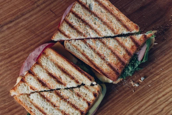 Twee broodjes op een houten achtergrond, Top uitzicht. Een stapel Panini met ham, kaas en sla sandwich op een snijplank — Stockfoto