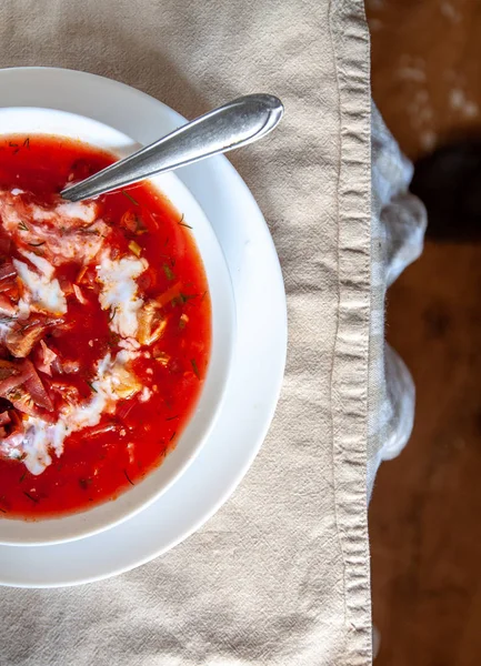 Hagyományos ukrán-orosz paradicsomos borscs leves tejföllel, fehér lemezen az asztalon. Megtekintés felülről. — Stock Fotó