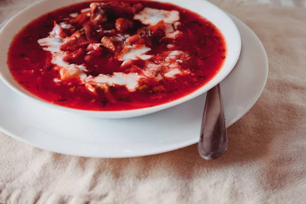 Sopa tradicional de borscht de tomate ucraniano-russo com creme azedo em uma placa branca na mesa. Vista de cima . — Fotografia de Stock