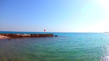 Kızıldeniz'deki bir iskelede tehlikeli kırmızı bayrak, Mısır. Güneşli rüzgarlı gün, geniş açı. Yavaş çekim, standart hareket. Skyline
