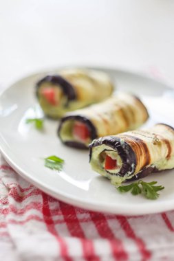 hafif bir arka plan üzerinde beyaz bir tabak üzerinde kızarmış patlıcan, süzme peynir ve domates geleneksel çanak üç rulo. Minimalizm. Yukarıdan görüntüle