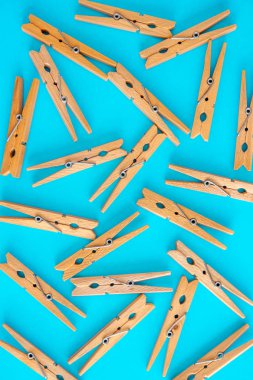 Wooden yellow clothespins are scattered on a cyan-blue background. Frame of clothespins. View from above. Copy space. Flat lay. The concept is natural, eco-friendly clipart