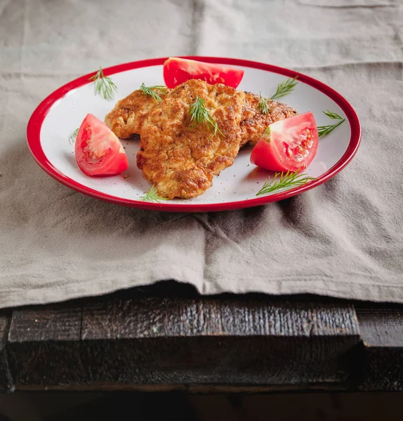 Сочные мясные отбивные из курицы и помидоры на белой тарелке на простом светлом льняном фоне подаются с вилкой и ножом — стоковое фото