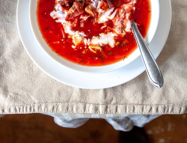 Traditional Ukrainian-Russian tomato borscht soup with sour cream in a white plate on the table. View from above. — Stock Photo, Image