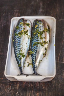 Yeşiller ve otlar iki çiğ balık uskumru karanlık bir arka planda pişmiş olacak. Yukarıdan görüntüle. Retro etkisi