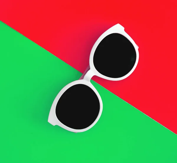 Sonnige, stylische weiße Sonnenbrille vor leuchtend grün-cyanfarbenem und rot-orangefarbenem Hintergrund, Draufsicht, isoliert. Kopierraum. flache Lage — Stockfoto