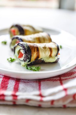 hafif bir arka plan üzerinde beyaz bir tabak üzerinde kızarmış patlıcan, süzme peynir ve domates geleneksel çanak üç rulo. Minimalizm. Yukarıdan görüntüle