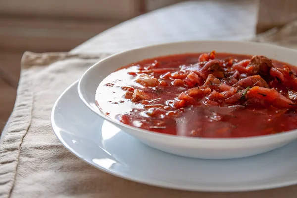 Traditional Ukrainian-Russian tomato borscht soup with sour cream in a white plate on the table. View from above. — Stock Photo, Image