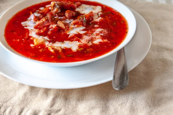 Sopa tradicional de borscht de tomate ucraniano-russo com creme azedo em uma placa branca na mesa. Vista de cima . — Fotografia de Stock