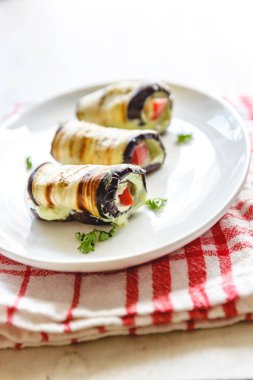 hafif bir arka plan üzerinde beyaz bir tabak üzerinde kızarmış patlıcan, süzme peynir ve domates geleneksel çanak üç rulo. Minimalizm. Yukarıdan görüntüle