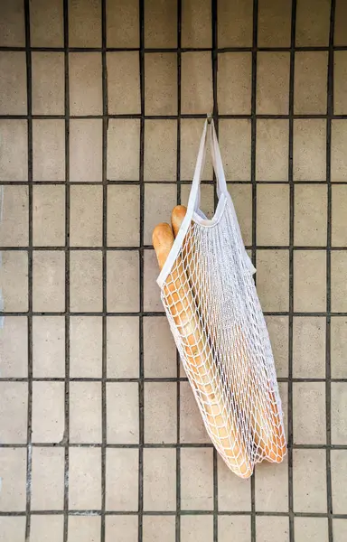 복고풍 벽돌 벽 배경에 매달려 문자열 가방에 신선한 장미 바게트. 맨 위 보기, 복사 공간 — 스톡 사진